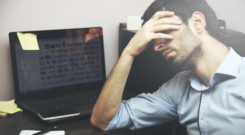 streesed man hold his head by work laptop
